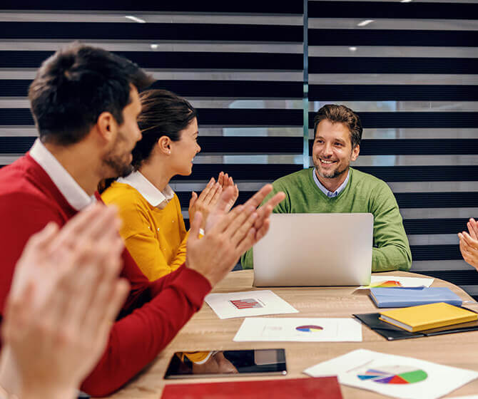 Group of professionals around a table clapping - Stock + Option Solutions Client Success Stories